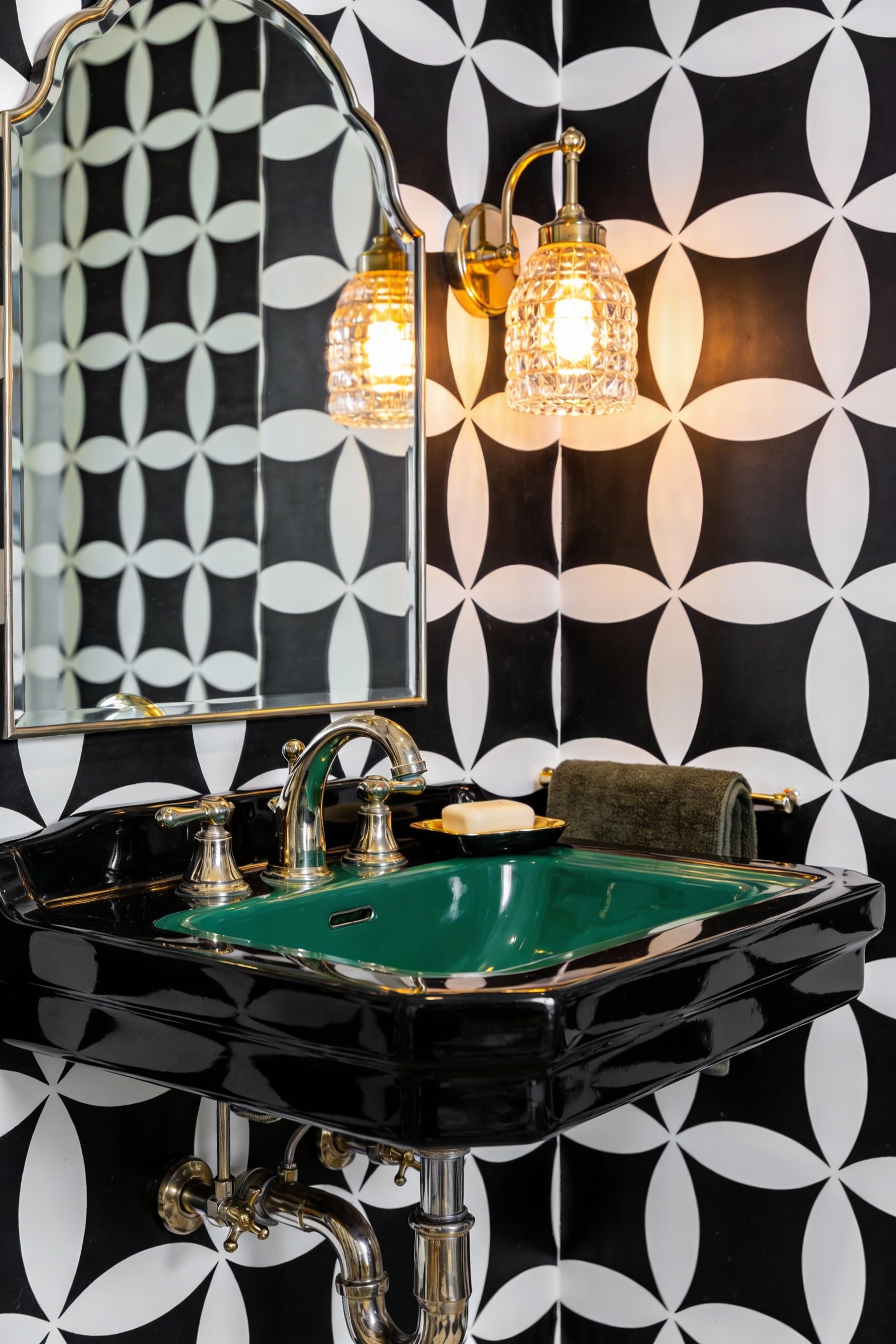 Close-up detail shot of a high-impact powder room vignette: bold high-contrast geometric wallpaper (black and white) fil